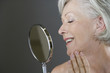 A senior woman looking at her face in the mirror