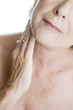 A senior woman touching her neck