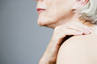 A senior woman applying moisturising cream to her shoulder