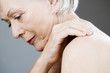 A senior woman applying moisturising cream to her shoulder