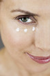 A middle-aged woman applying eye cream