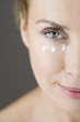 A middle-aged woman applying eye cream