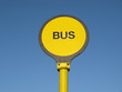 Yellow bus stop sign over blue sky background