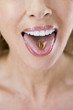 A middle-aged woman with a vitamin capsule on her tongue