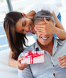 Pretty woman covering her husband's eyes to surprise him with a