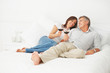 Couple lying on their bed having a glass of wine
