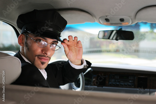 Photo: Portrait of a chauffeur sitting in a car saluting a viewer Portrait of a chauffeur sitting in a car saluting a viewer