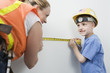 Foto: View of a woman and boy measuring wall with tape measure. View of a woman and boy measuring wall with tape measure.