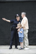 Foto: Woman police officer directing a senior man with a boy. Woman police officer directing a senior man with a boy.