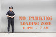 Woman police officer standing in front of a parking zone.