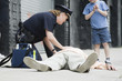 Photo: Woman police officer administering first aid to a senior man. Woman police officer administering first aid to a senior man.