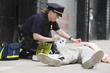 Woman police officer administering first aid to a senior man.