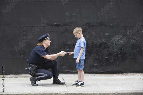 Foto: Woman police officer talking to a boy. Woman police officer talking to a boy.