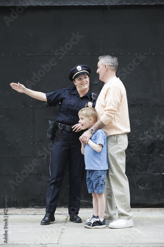 Foto: Woman police officer directing a senior man with a boy. Woman police officer directing a senior man with a boy.