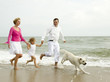 Family playing with dog on the beach