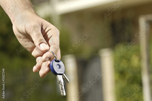 Photo: young man and new home, looking building with door key in hand; young man and new home, looking building with door key in hand;