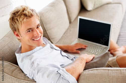 Photo: Handsome young man working on a laptop at his home Handsome young man working on a laptop at his home