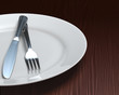 Photo: Clean plate & cutlery on dark woodgrain table Clean plate & cutlery on dark woodgrain table