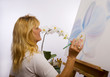 A female artist painting orchids on canvas in her studio