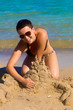 Girl at the seashore making a sand lobster