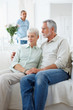 Retired couple at home with a servant in the background