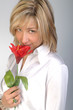 Ragazza bionda annusa un fiore rosso Ragazza bionda annusa un fiore rosso