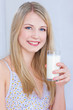 Smiling blond hair woman holding glass of milk
