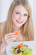 Pretty blue eyes woman eating tomato and holding salad on plate