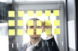 mann arbeitet konzentriert hinter scheibe mit post it