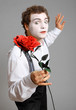Man holding a rose. mime on grey background