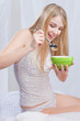Young woman in bedroom holding spoon and plate, ready to eat