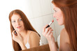 Body care series - Beautiful red hair woman applying lipstick