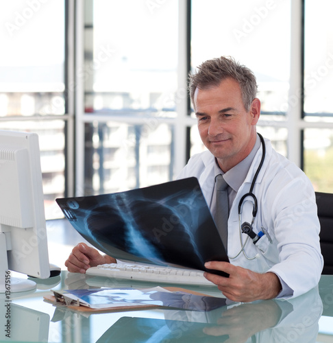 Photo: Mature Doctor looking at an x-ray Mature Doctor looking at an x-ray