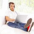 Young woman sitting on couch and working on laptop