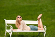Attractive young woman lying on white bench