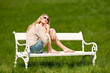 Young woman sitting on white bench