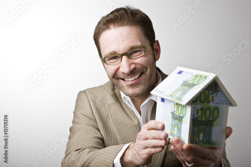 Junger Mann mit Haus aus Geldscheinen