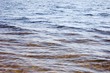 Bottom of the lake covered by stones seen through waves