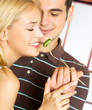 Young happy couple playfully eating. Focus on woman.