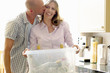 Mature woman holding recycling container of glass bottles with man kissing her cheek