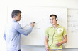 Teacher at board trying to explain to a student with headphones
