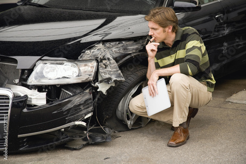 Photo: Insurance adjuster assessing damage to car Insurance adjuster assessing damage to car