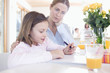 Portrait of mother helping daughter with homework