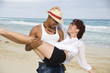 Man carrying young woman on beach, smiling, Havana, Cuba