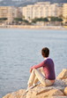 Girl is resting on stones of pier with Cannes city background Girl is resting on stones of pier with Cannes city background