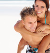 Young female being piggybacked by boyfriend at the beach