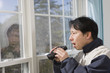 Man looking out a window with binoculars