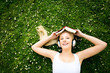Woman lying on grass with book and headphones