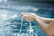 Water dripping from the cupped hands of a woman