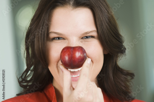 Photo: Woman holding a nectarine in front of her nose Woman holding a nectarine in front of her nose